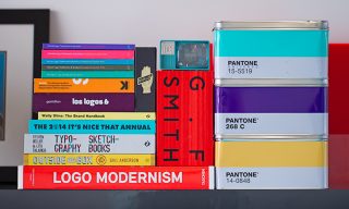 Must Reads for Designers A stack of books related to design, next to a tins showing pantone colors