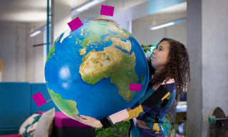 Brand Consistency A woman struggling to hold a large globe that has flags in several places