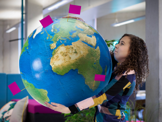 Brand Consistency A woman struggling to hold a large globe that has flags in several places