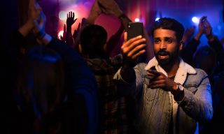 ScreenSpace campaign image of young man holding a mobile phone in a crowd