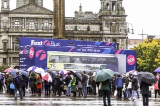 Photo of real bus inside of a giant toy box with people standing around it