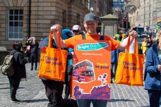 Photo of man holding Bright Bus Tours tote bags