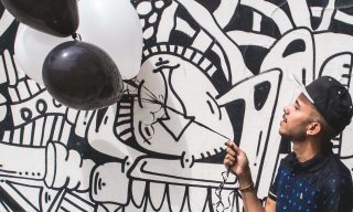 12 Practical Ideas for Creative Freelancers Looking to Get Paid Work man holding a balloon in front of a wall covered in black and white illustrations