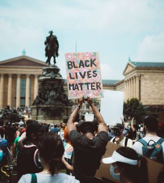 A person of colour holding a placard saying “Black Lives Matter”.