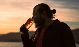 How to Use Content to Prototype, Test, and Evolve Your Brand Man drinking a pint of Tennent's lager on a beach with sunset in the background