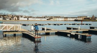 Person standing on a doc with a camera