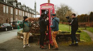 Behind the scenes shooting someone in a phone booth with two video cameras
