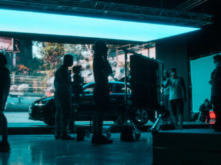 Virtual Production | Behind the Scenes photo of two people on virtual production stage with lots of neon lights adjusting equipment