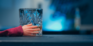 Behind the Scenes - Giant Whisky tiny rubber hand holds a glass of whisky