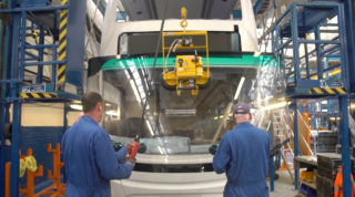Two men installing windshield for New Buses Assembly