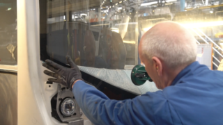 Man installing windshield for New Buses Assembly