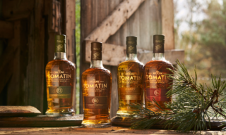 Tomatin 'To What Matters' Brand Repositioning Film & Campaign - Bottle Shots four bottles of Tomatin whisky sitting in front of a wood floor with pine branch in front of them