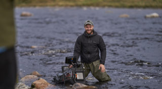 man standing in a river with waiters and waterproof camera