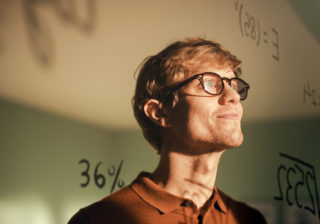 man with glasses looking out a window