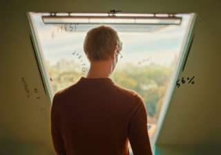 man with glasses looking out a window