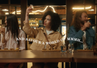 woman with dark curly hair standing at The Singleton Bar holding Whisky glass up to the light
