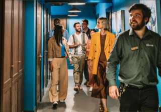 Several people walking down a blue hallway smiling and taking The Singleton Distillery Tour