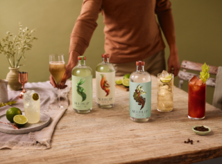 Man reaching over a table full of drinks and spirit bottles for a non alcoholic cocktail