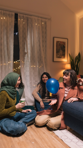 Blue Balloon Campaign - Europe photo of four women sitting in a livingroom with party hats on. One of them is keeping a blue balloon up in the air