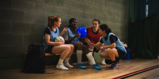 photo of four people in a gym. One of them is holding a blue balloon