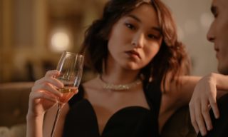 The Luxury Spectrum Model Woman in an elegant black dress holding a glass of champagne