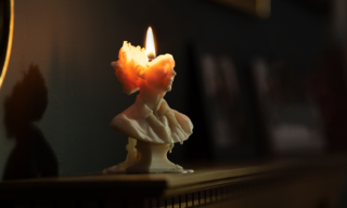 Slow the Burn photo of a white marble bust candle that is halfway burned through