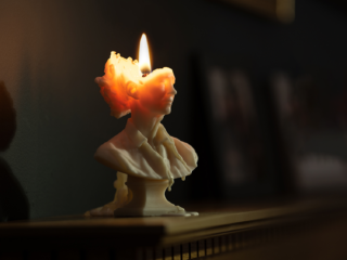 Slow the Burn photo of a white marble bust candle that is halfway burned through