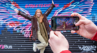 Mural of the U22 wings with woman taking selfie in front of it.