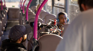BTS shot of Cameraman on bus, shooting Main Character whilst they listen to music in their seat.