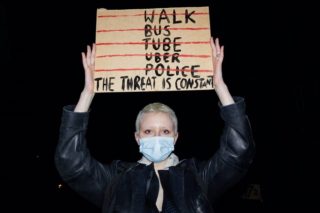 photo of woman holding up a sign in protest that says 