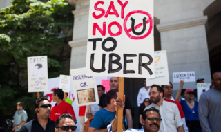 Say No to Uber (Credit - New York Times) photo of people holding signs, protesting Uber. One sign says