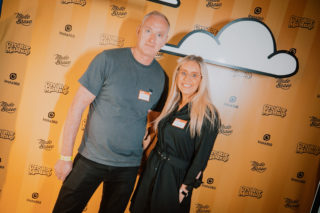 photo of a man and woman posing in front of the creatormashup step and repeat wall