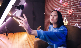 Creator Economy: The Future of Marketing? woman using a phone and ring light to create social media content