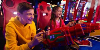 photo of two kids playing arcade games with laser guns