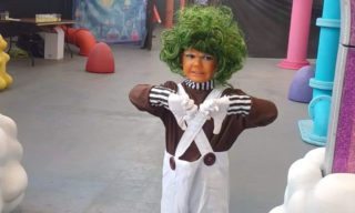 The Willy Wonka Experience photo of a child dressed up as an oompa loompa with two thumbs down