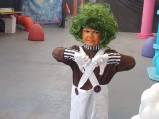 The Willy Wonka Experience photo of a child dressed up as an oompa loompa with two thumbs down
