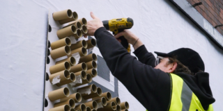 Catherine McEwan X MadeBrave - 'A Sh*t Idea' photo showing a man hanging the OOH QR code on the billboard