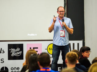 photo of jamie axford, creative director at madebrave, standing on a conference stage with an audience watching