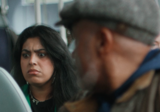 photo of a man looking at a woman who is eating crisps on a bus