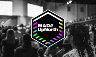 MAD//UpNorth a blurry black and white photo of people at a conference with a colorful MAD//UpNorth logo over the top