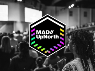 a blurry black and white photo of people at a conference with a colorful MAD//UpNorth logo over the top
