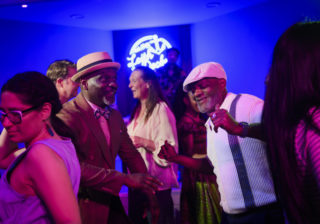 Two men dancing in a club with pink and purple lights
