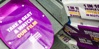 photo of a purple toilet seat with 'take a seat and watch our film' written on it