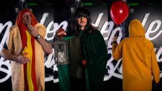 a photo of a man in a hotdog costume, a man in a cloak, and a person wearing a yellow coat with a red balloon
