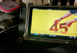 Tunnock's Brand Film - Behind the Scenes a photo of a monitor showing a foil-wrapped red 45 with with hands holding it up on all on a yellow background