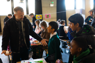 Kids Make Glasgow - Magic! a photo of a man doing a magic trick for a bunch of kids with all of them smiling with delight
